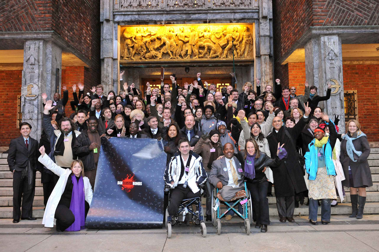 Viele Menschen, ein paar im Rollstuhl, stehen vor einem Gebäude und jubeln