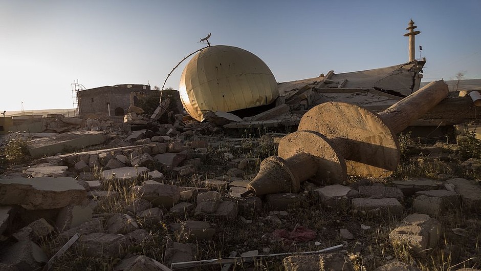 Ein Trümmerhaufen aus dem eine goldene Kuppel und die Spitze einer Moschee herausschauen.