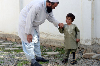 Der sechsjährige Sayed bei einer Therapie. Er lächelt leicht und hält die Hand seines Physiotherapeuten.