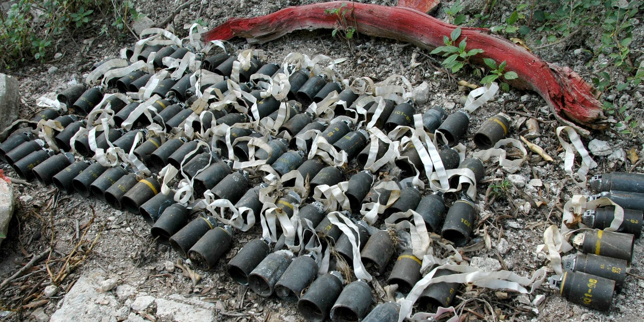 Eine Vielzahl an Submunitionen aus Streubomben liegen aufgereiht auf dem Boden.