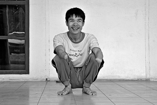 Phongsavath hockt lächelnd auf dem Boden.
