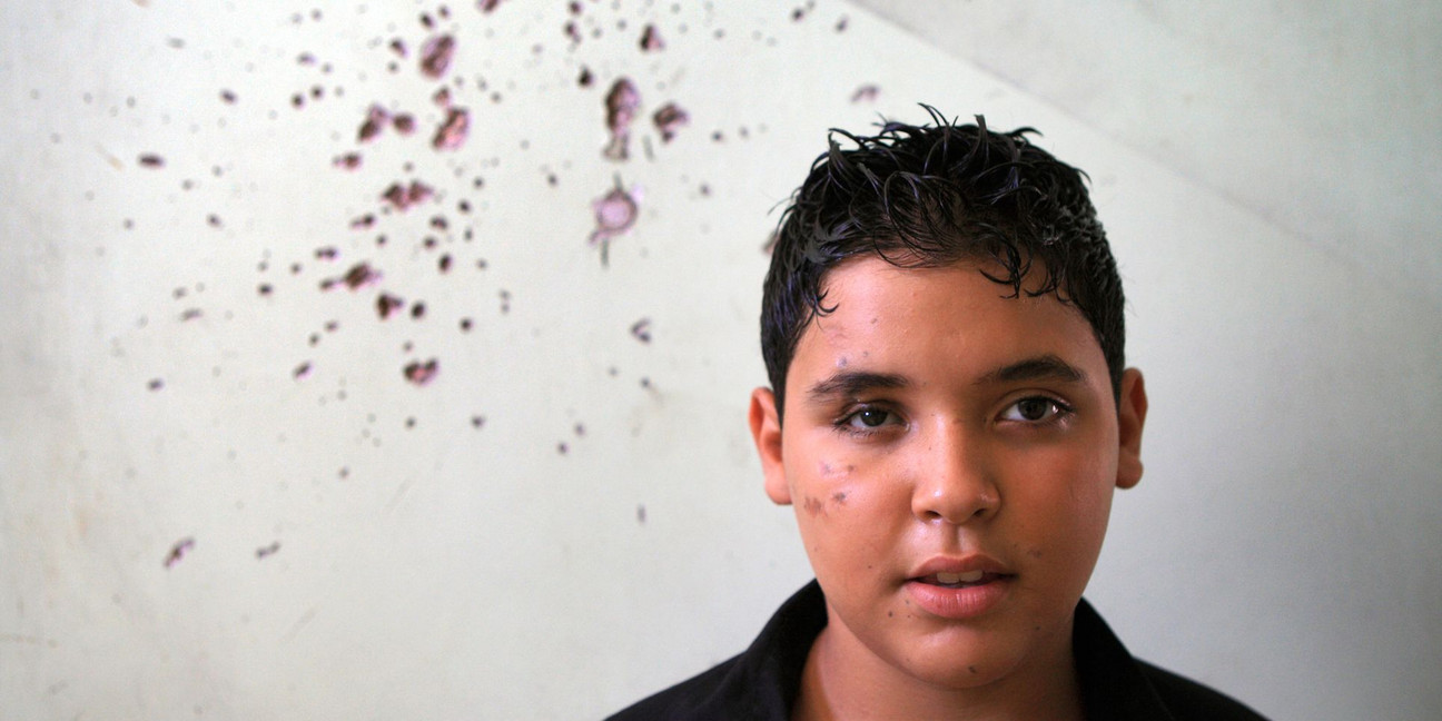 Mohammed vor einer Wand mit Einschusslöchern.