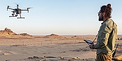 Ein Mann in der Wüste steuert eine Drohne